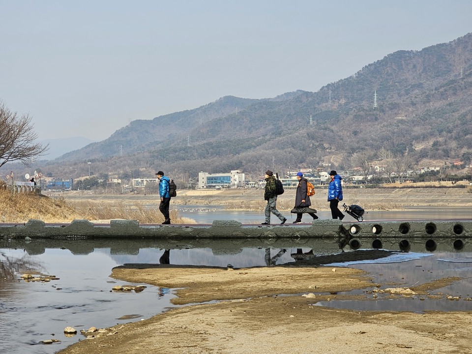 23일 오후 2시50분께 겨울철새인 ‘고니’ 촬영을 위해 하남시 팔당대교 남단 ‘한강 철새 관찰 포인트’를 찾은 프로사진작가들이 카메라와 삼각대 등 여러 장비가 담긴 캐리어를 끌며 산곡천을 건너고 있다. (사진=장은기 기자)