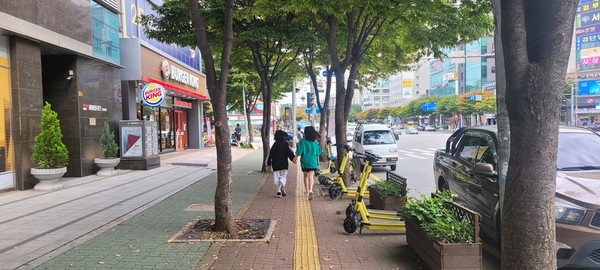 인천시 서구 마전동의 한 도로변에 주차된 공유형 전동 퀵보드 옆으로 보행자들이 걸어가고 있다. (사진=남용우 선임기자)