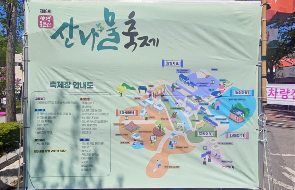 용문산 산나물축제 행사장에 설치된 축제 안내도 앞에서 방문객들이 동선을 확인하고 있다.