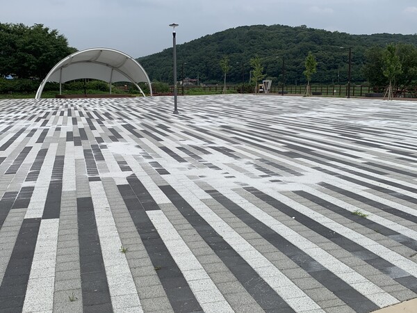 광장에는 주변 자연경관과 전혀 어우러지지 않는 이질적인 흑백 패턴의 보도블록이 메우고 있고, 그 위로는 마감 처리를 위해 뿌려진 모래가 정리되지 않은 채 사방에 방치되어 있다. /사진=오기춘 기자